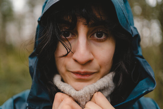 Portrait of woman wearing hooded raincoat shivering in rain