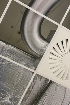 Close-up view of building interior showing shiny metal ductwork and air vent.