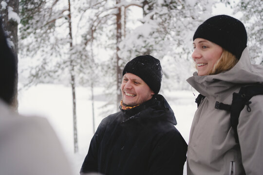 Smiling couple wearing knit hat and warm clothes in winter fores