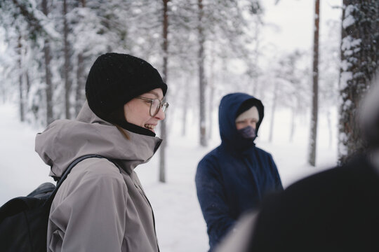 Side view of smiling woman talking with family in winter forest