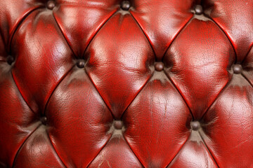 Naklejka premium Detailed texture of red leather upholstery with tufted diamond pattern and buttons