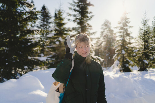 Thoughtful woman touching temple while standing in winter forest