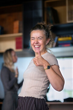 Portrait of happy businesswoman showing thumps up sign while standing in office