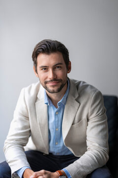 Portrait of young male entrepreneur wearing blazer sitting in office
