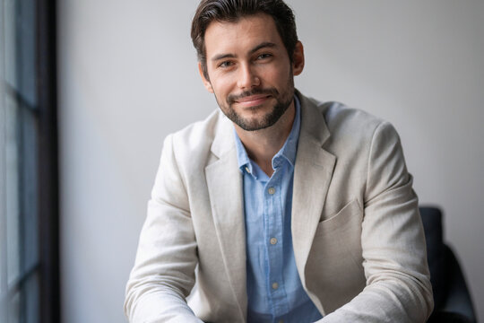 Portrait of smiling male business entrepreneur wearing blazer sitting in office