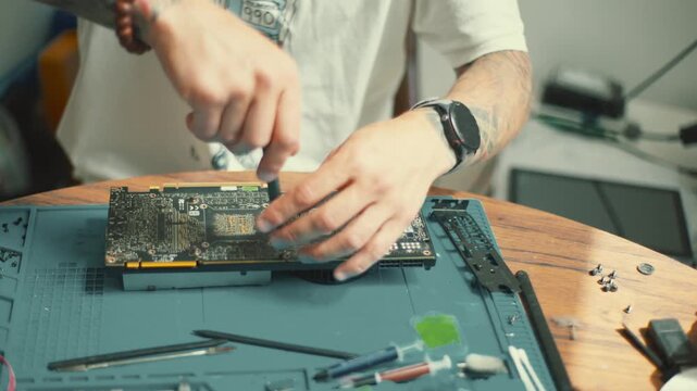 Repairing a computer graphics card with tools on a wooden table in a home office setting