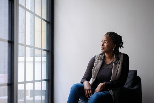 Female entrepreneur looking out window while sitting on armchair in new office