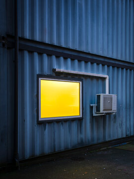 AC unit next to illuminated window on corrugated wall