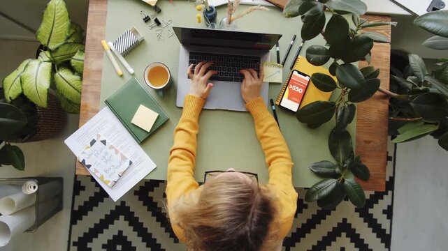 Top Down View of Freelancer Woman Working at Desk with Documents and Laptop