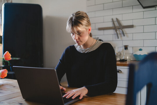 Focused female freelancer using laptop while working at home