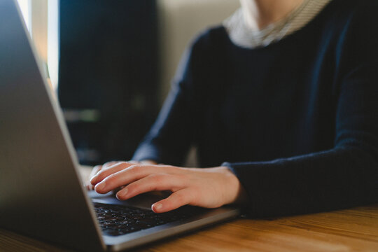 Hand of businesswoman typing on laptop while working from home