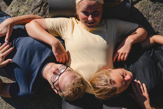 Directly above shot of man and woman lying on female friend at sunny day