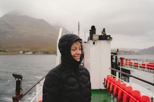Smiling woman wearing hooded jacket standing in ship during weekend travel