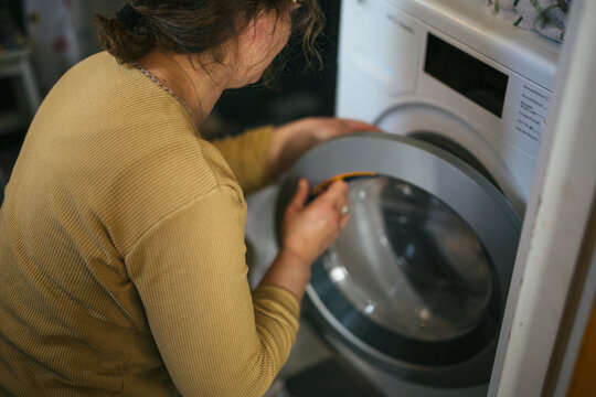 High angle view of woman opening door of washing machine