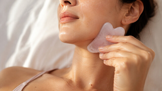 Close-up of a woman indulging in a rejuvenating skincare routine with a gua sha tool, promoting healthy, radiant skin and self-care rituals