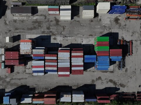 Aerial view of colorful shipping containers stacked in an industrial yard with long shadows on the asphalt ground in Cincinnati, OH, United States.