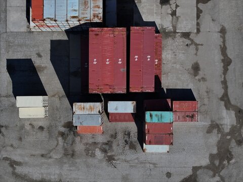 Aerial view of stacked shipping containers in various colors on a weathered asphalt lot with long shadows Cincinnati, OH, United States.