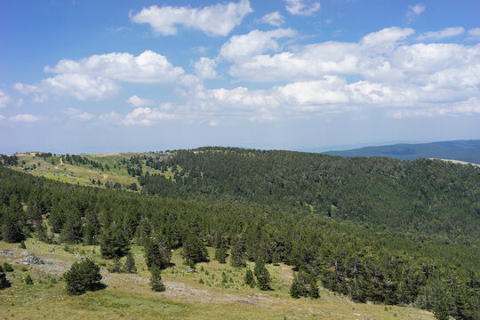 Panoramic scenic view of Mount Ida (Kaz Daglari) national park with green pine forests, rocky slopes, and misty mountain ranges under a clear blue sky. Nature tourism, hiking, and travel  in Canakkale