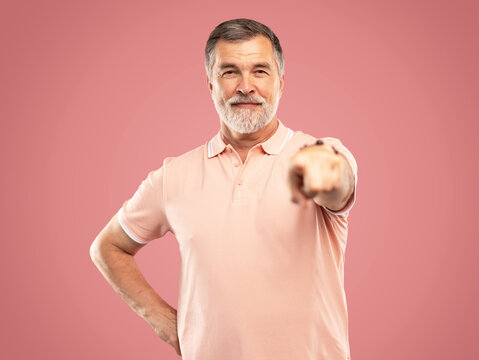 I choose you and order. The smiling mature businessman point you, portrait on pink studio background