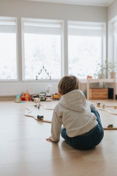 Rear view of baby boy playing with toy cars in bedroom at home