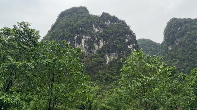 Limestone karst mountains covered in dense jungle vegetation under a cloudy sky in Ninh Binh, Vietnam landscape