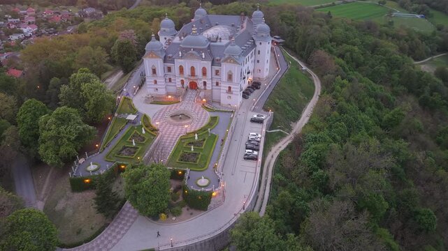 Majestic aerial view of the historic Halicsky Castle in Slovakia. The baroque palace is perched on a hill, surrounded by dense green forest