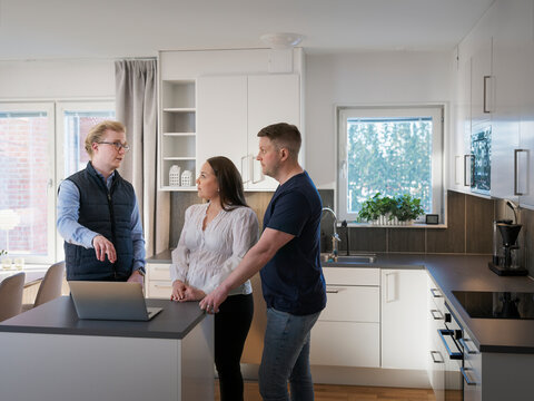 Male architect explaining home improvement plan on laptop to couple in kitchen