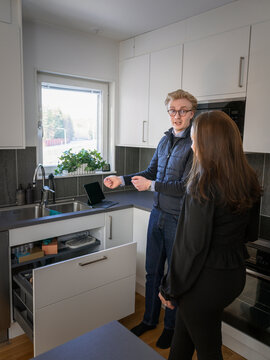 Male technician explaining dishwasher problems to homeowner while standing in kitchen