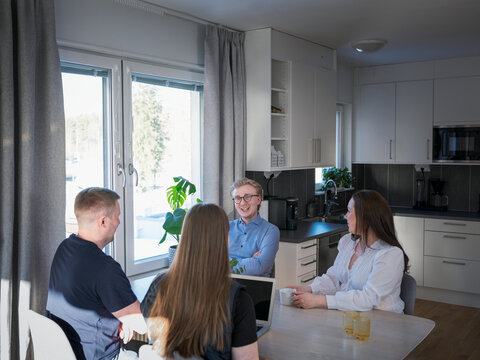 Family members talking with female agent while sitting at table in home