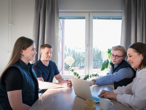 Man and woman examining house improvement plan on laptop while sitting with agent at table