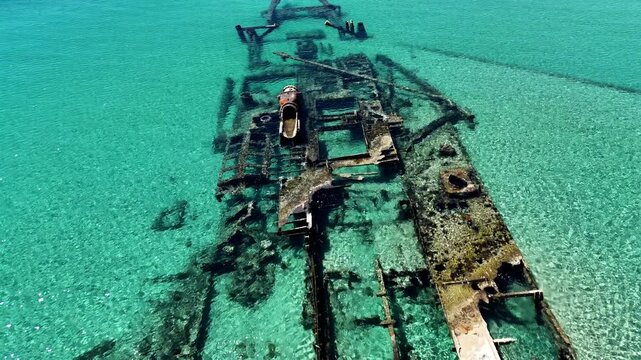 Aerial view of the famous Epanomi shipwreck submerged in crystal clear turquoise waters near the sandy beach spit in Halkidiki, Greece.