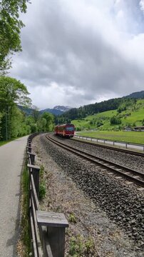 Zillertal, Austria: 10.5.2026: Red Zillertalbahn passenger train traveling on curved railway tracks through the scenic alpine valley of Zillertal in Tyrol, Austria. Dramatic clouds, green hills and pe