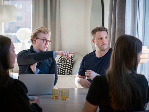 Male agent pointing while explaining home improvement plan to family members while sitting at table