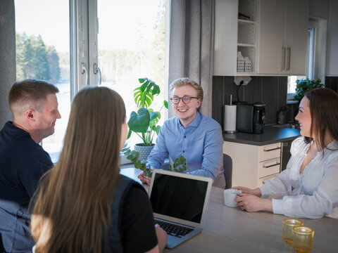 Smiling man talking with female architect while sitting at table in home
