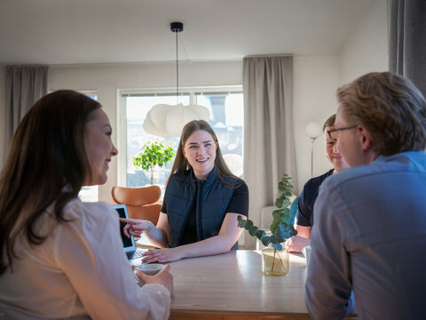 Smiling female building contractor explaining plan on laptop to family at home