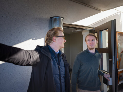 Male property caretaker explaining while talking with man standing at doorway of house