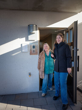 Happy female maintenance worker standing with resident at doorway of house