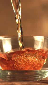 A super slow motion jet of tea pours into a cup of air bubbles. On a brown background. Filmed on a high-speed camera at 1000 fps.