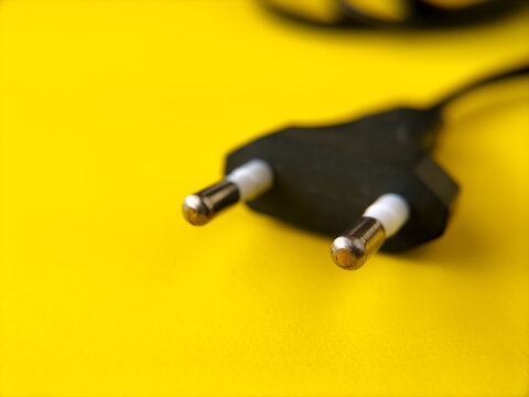 European two-pin power cord on bright yellow background. Concept of electricity, energy, technology, connection, and power supply.