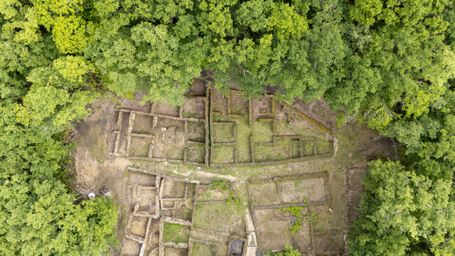 Aerial view of the ancient stone foundations of Castro de Armea surrounded by a dense green forest in Allariz, Province of Ourense, Spain.