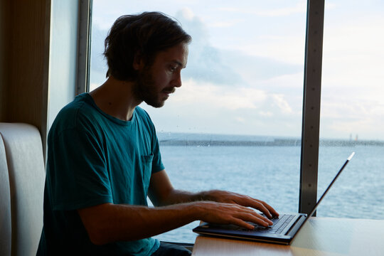 Male freelancer working on laptop while traveling in ship