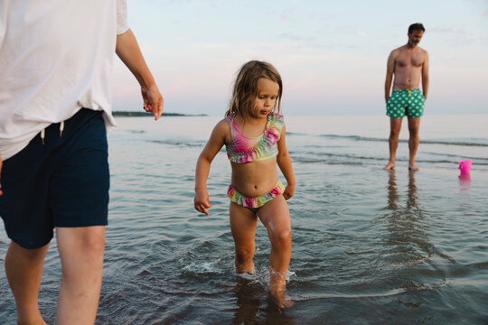 Cute girl wearing swimwear walking in sea water at beach with brother