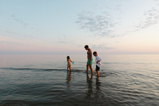 Full length of father and children spending leisure time in water at sea