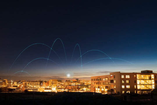 Digitally generated image of network lines above illuminated city against clear sky