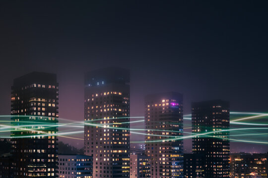 Digitally generated image of network lines passing through illuminated buildings under clear sky at night
