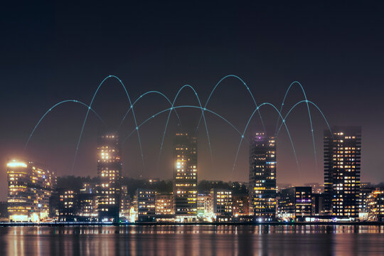 Digitally generated image of network lines passing above illuminated buildings under clear sky at night
