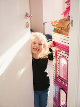 Portrait of blond girl with gap toothed leaning at bedroom door