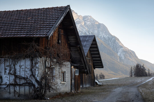 Rustic farm buildings in Mieming, Tyrol with snowy mountains in the background. A peaceful alpine rural scene ideal for travel and landscape themes.