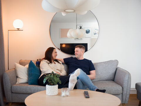 Smiling couple spending leisure time with each other while sitting on sofa at home