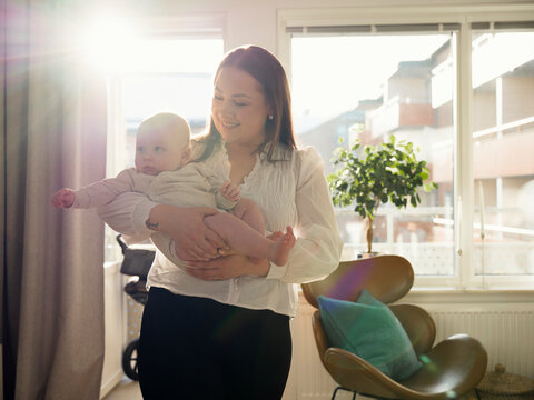 Smiling woman spending leisure time with cute baby boy at home